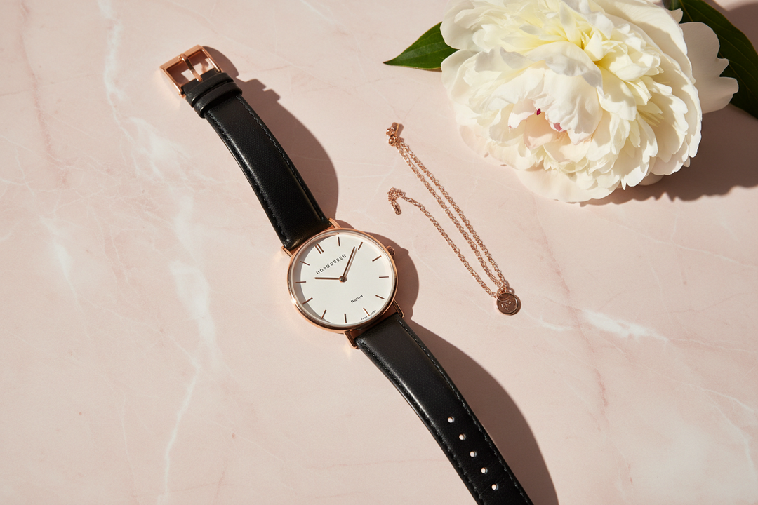 Nordgreen Native 32mm Rose Gold Case Black Leather watch flat lay on blush marble with white peony